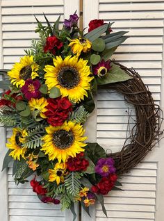 a wreath with sunflowers, roses and greenery hangs on the front door