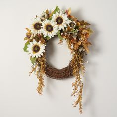 a wreath with sunflowers and greenery hanging on the wall