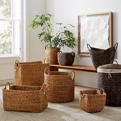 several woven baskets sitting on the floor in front of a window