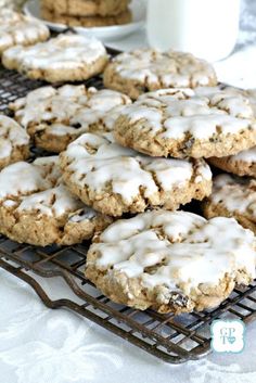 cookies with white icing on a cooling rack next to a cup of coffee and glass of milk