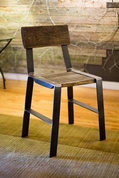 a wooden chair sitting on top of a hard wood floor next to a wall covered in graffiti