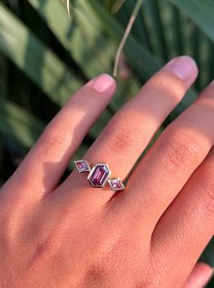 a woman's hand with a ring on it and a plant in the background