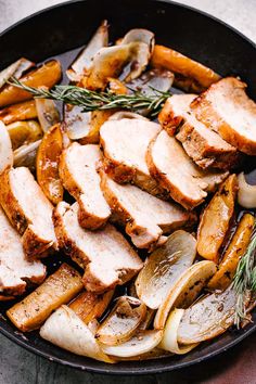 sliced pork, onions and carrots in a skillet with rosemary sprigs