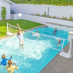 people are playing volleyball in an outdoor swimming pool with net on the side, and one person is jumping up to hit the ball