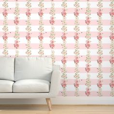 a white couch sitting in front of a wall with pink and green flowers on it