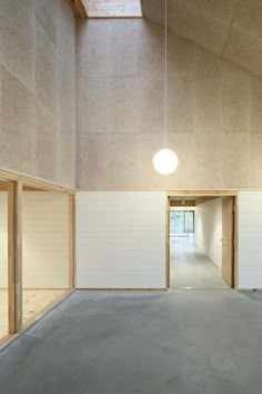 an empty room with white walls and wooden paneling on the ceiling is lit by a round light