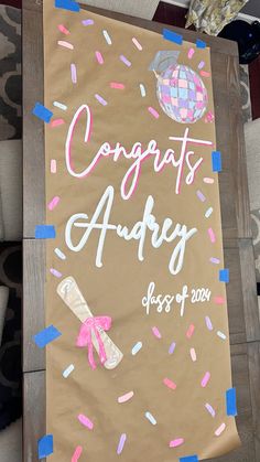 a brown sign with pink and blue sprinkles on it that says congrats andy