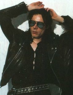 a man with sunglasses on his head wearing a black leather jacket and silver bracelets