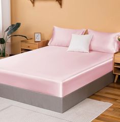 a bed with pink sheets and pillows in a room