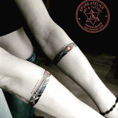 two people with tattoos on their legs sitting next to each other, both wearing bracelets