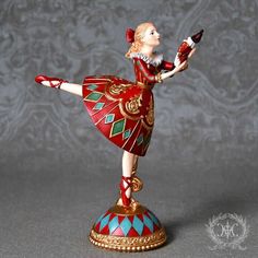 a figurine of a woman in red and gold is holding a wine bottle