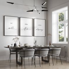 a dining room table with four chairs and three framed pictures on the wall above it