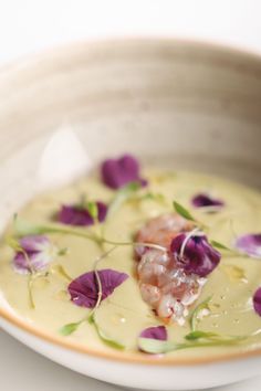 a white bowl filled with soup and purple flowers