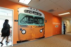 people are standing in an orange room with a bus painted on the wall