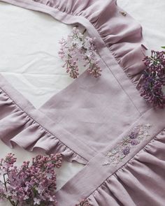 lilac flowers are laying on the ground next to a piece of cloth with ruffled edges