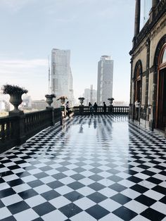 a black and white checkered floor in an old building with tall buildings behind it