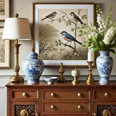 two blue and white vases sitting on top of a wooden dresser next to a painting