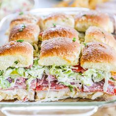 a sandwich cut in half sitting on top of a glass pan filled with meat and coleslaw