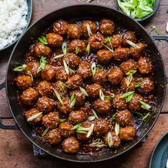 meatballs and rice in a skillet on a wooden table with chopsticks