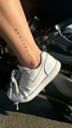 a person's foot with a tattoo on the side of their leg, sitting on a motorbike