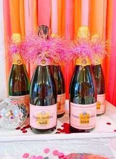 three bottles of champagne are sitting on a table with confetti and streamers