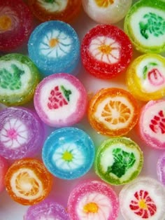 many different colored candies are arranged in the shape of fruit slices and leaves on a white surface