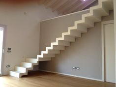 an empty room with white stairs and hard wood flooring