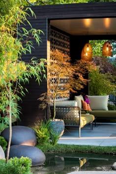 an outdoor living area with furniture and water feature in the foreground, surrounded by greenery