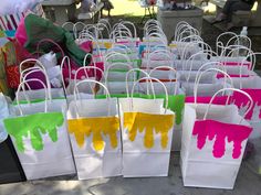 bags with paint splattered all over them are on display at an outdoor market