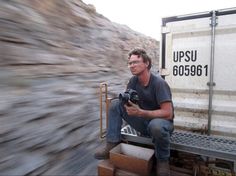 a man sitting on the back of a truck holding a camera