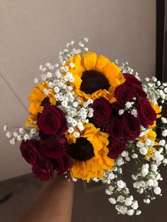 a bouquet of sunflowers and red roses in someone's hand with baby's breath