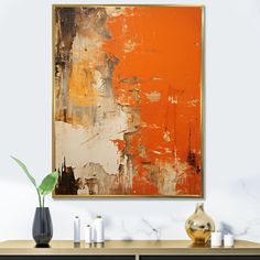 an orange and white abstract painting hangs on the wall next to a black cabinet with candles