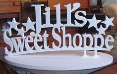 a sign that says lil's sweet shoppe on top of a white table