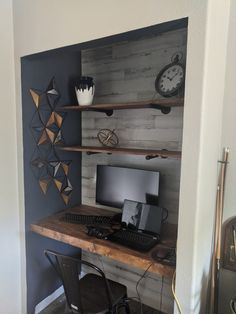 a desk with a computer on top of it in a room next to a wall