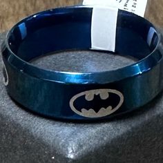 a batman bracelet with a tag on it sitting on top of a gray cloth covered table