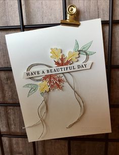 a handmade card with leaves on it that says have a beautiful day, hanging from a wire