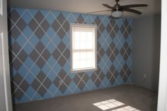 an empty room with a ceiling fan and blue argyle wallpaper on the walls in it