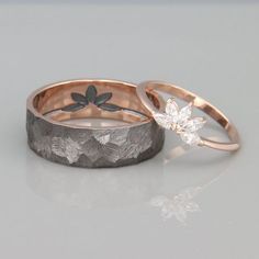 two wedding bands with flowers and leaves on them, one in gold and the other in silver