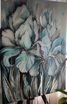 a painting with blue and white flowers painted on it's canvases next to a potted plant