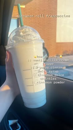 a person holding up a plastic cup filled with milkshake and toppings in the back seat of a car