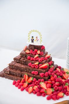 a chocolate cake with strawberries on top and a small wedding cake in the middle