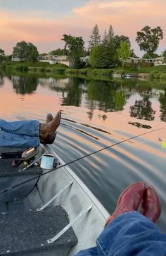 a person is sitting in a boat on the water with their feet propped up and fishing