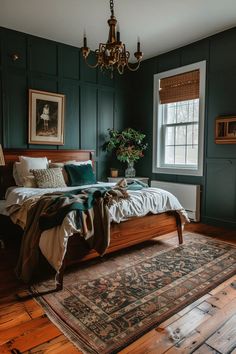 a bedroom with dark green walls and wood flooring, a large bed in front of a chandelier