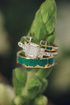 A matching wedding ring set from Staghead Designs sits on the bud of a flower. This 14K yellow gold set features a custom emerald cut moissanite engagement ring that has five stones paired with an Art Deco style stacking band that has four rectangle malachite inlays. The other band is a "Helios" design mountain range band in 14K yellow gold with malachite inlays. Antler Wedding Rings, Emerald Cut Moissanite Engagement Ring, Staghead Designs, Emerald Cut Moissanite, White Gold Engagement Ring, Stacking Bands, Detailed Ring, Ceramic Rings, Custom Ring Designs