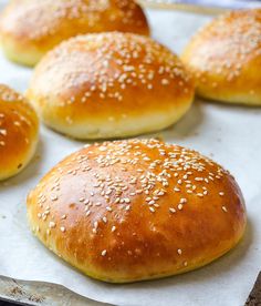 bread rolls with sesame seeds on top sitting on a baking sheet in front of an advertisement for the best hamburger buns recipe