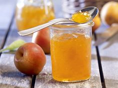 a spoon with some food in it sitting on a table next to apples and other fruit