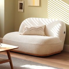 a white couch sitting on top of a hard wood floor next to a wooden table