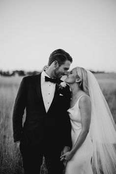 a bride and groom kissing in a field