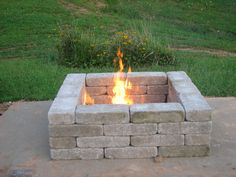 a fire pit sitting on top of a cement slab in the middle of a field