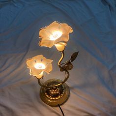 a lamp that is on top of a white sheet and has flowers in the middle